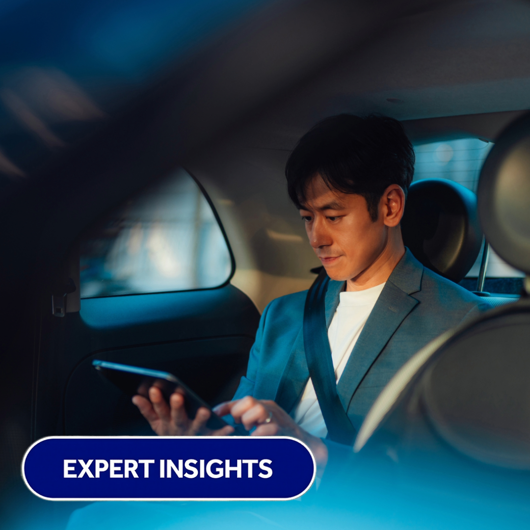 A smartly dressed man in the back of the car on his mobile phone